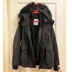 Black utility down jacket w/ a removable fur vest inside.